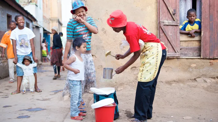Une femme entrain de servir du lait à un enfant et sa mère